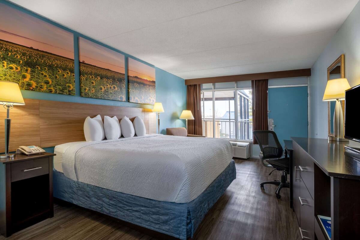 Habitación de hotel con una cama grande, dos lámparas de noche, un escritorio con una computadora y un televisor.