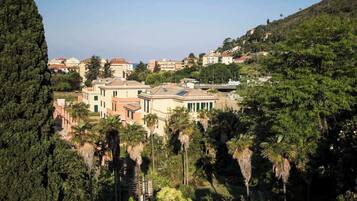 Eine mediterrane Villa mit Garten, umgeben von Hügeln und Wohnhäusern.