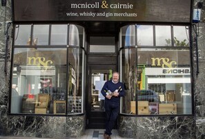 The entrance to a wine, whisky, and gin shop with large glass windows and a marble facade. - A luxurious Victorian mansion garden apartment (Broughty Ferry)