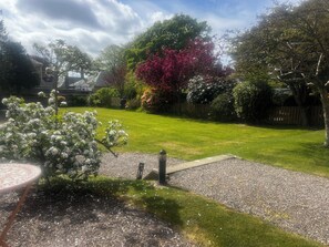 Un jardin bien entretenu, avec une pelouse, un chemin de gravier et une clôture en bois.