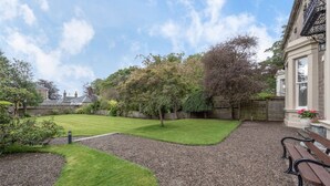 A well-maintained garden with a lawn, gravel paths, and a wooden bench. - A luxurious Victorian mansion garden apartment (Broughty Ferry)