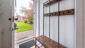 A room with a wooden bench, a coat rack with hooks, and a door leading to a garden. - A luxurious Victorian mansion garden apartment (Broughty Ferry)