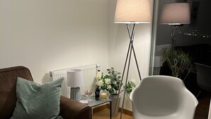 A modern living room with a brown sofa, a white armchair, a small table with a plant, and a floor lamp. - Appt terrasse vue mer, 2 chambres / Appt terrace sea view with 2 bedrooms (Trouville-sur-Mer)