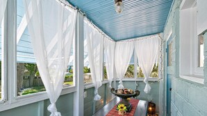 Eine überdachte Veranda mit Tisch, Stühlen und einer dekorativen Mitte.