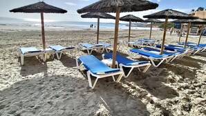 A beach with sun loungers and thatched umbrellas. - Frontline modern- Cabo del Playa- Apartment (Cabo Roig)