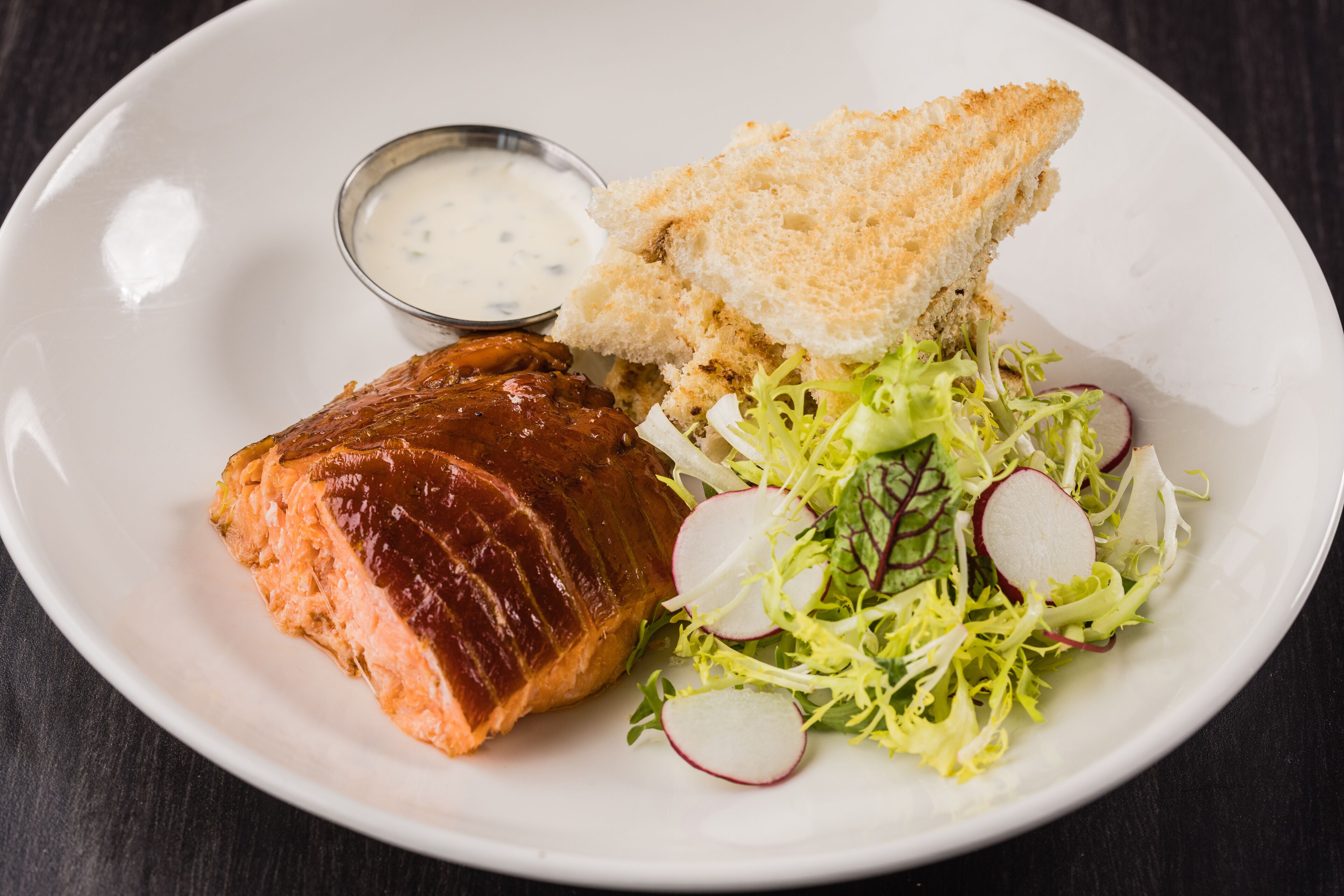 A plate with salmon, a salad, and a piece of bread.
