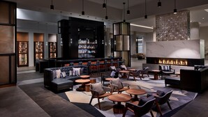 A modern lounge area with a bar, seating arrangements, and a fireplace. - Marriott Owings Mills Metro Centre (Owings Mills)