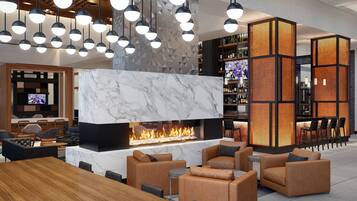 A modern lounge area with a marble fireplace, leather seating, and a bar area with shelves of bottles.