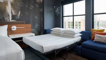 Una habitación de hotel moderna con una cama, un sofá y un ventanal que ofrece vistas de la ciudad.