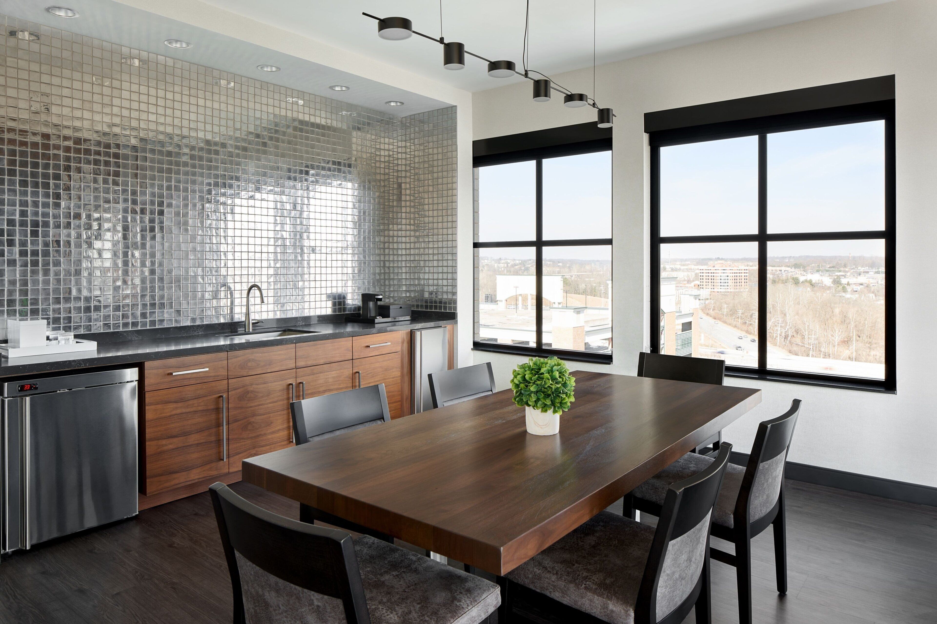 A modern kitchen with a large island, stainless steel appliances, and a view through large windows.