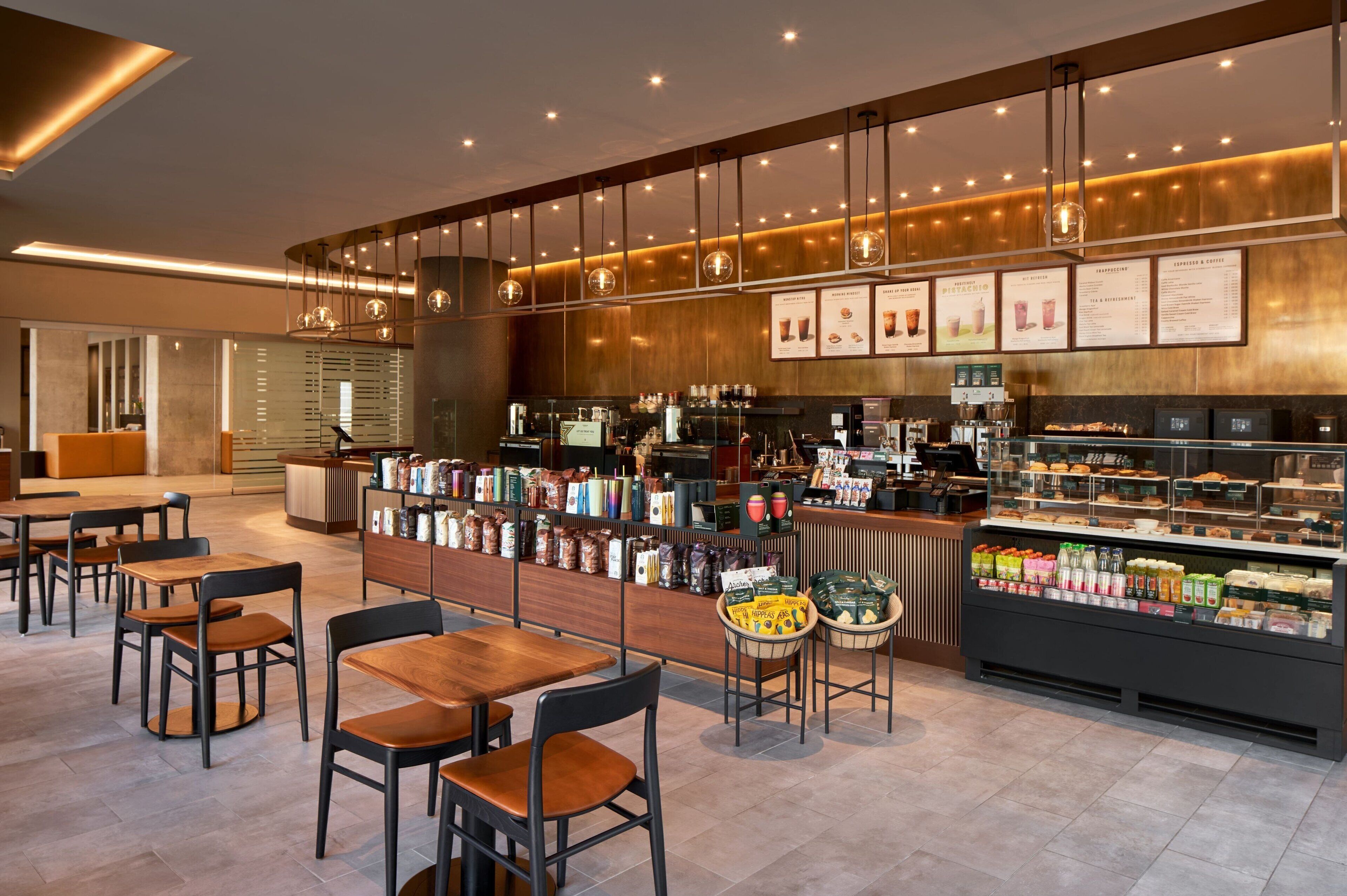 Un interior moderno de cafetería con mesas, un mostrador y una vitrina.