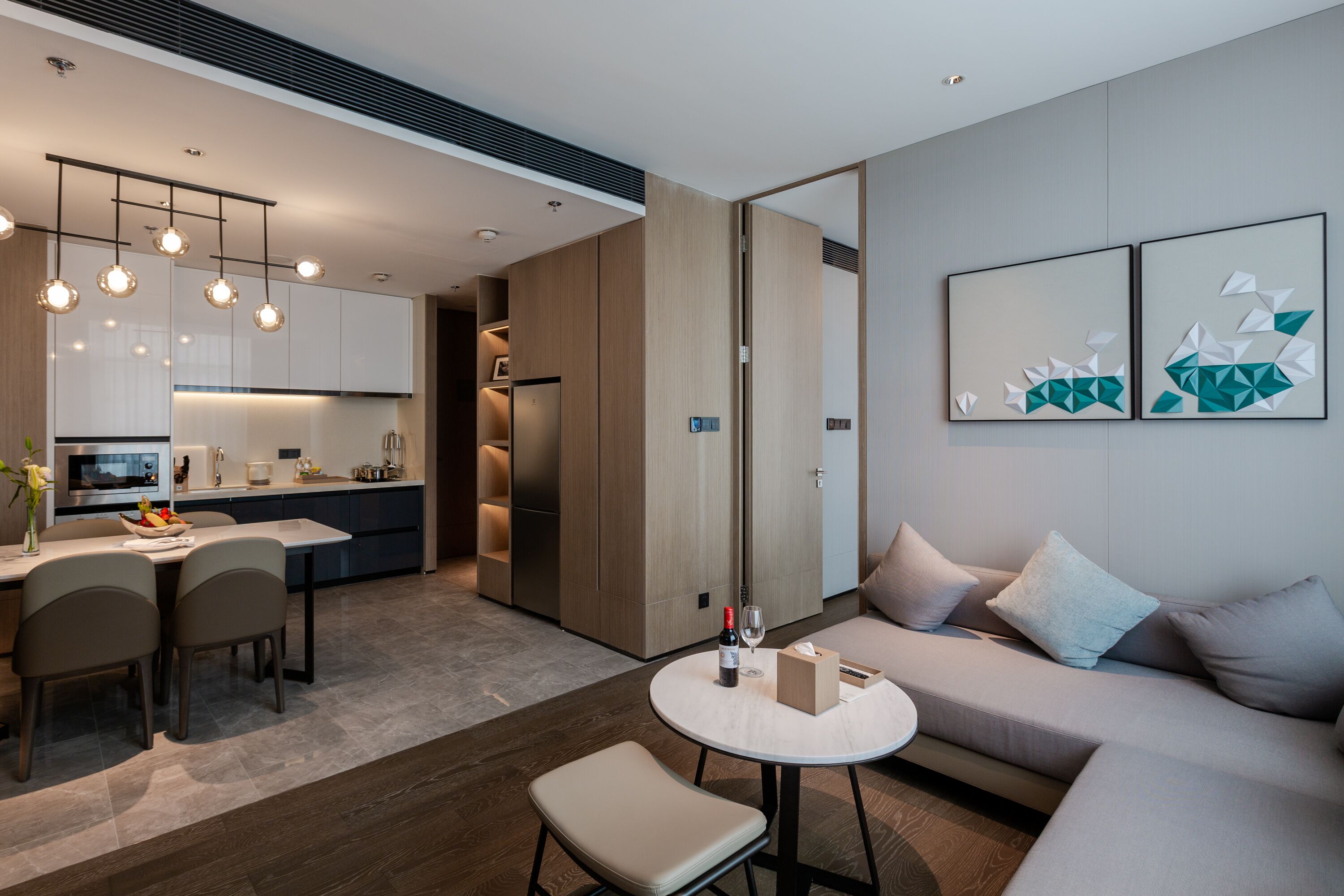 A modern living room with a sofa, a dining table, and a kitchen area.