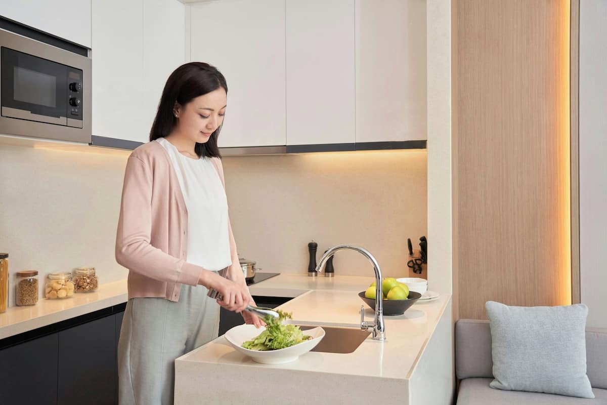 Una cocina moderna con microondas integrado, un lavamanos y un bol de ensalada.