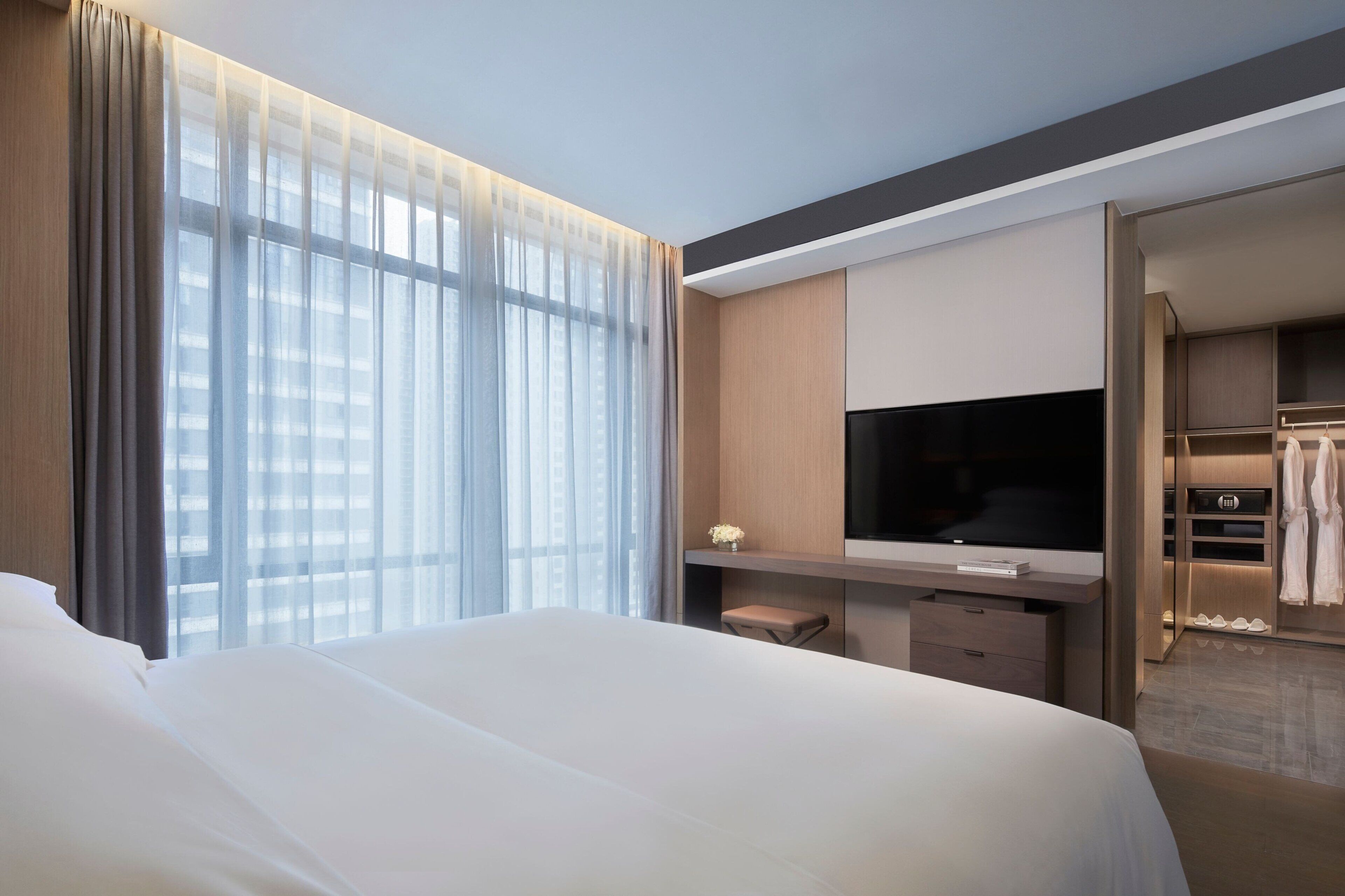 Una habitación de hotel con una cama grande, televisión, escritorio y vestidor.