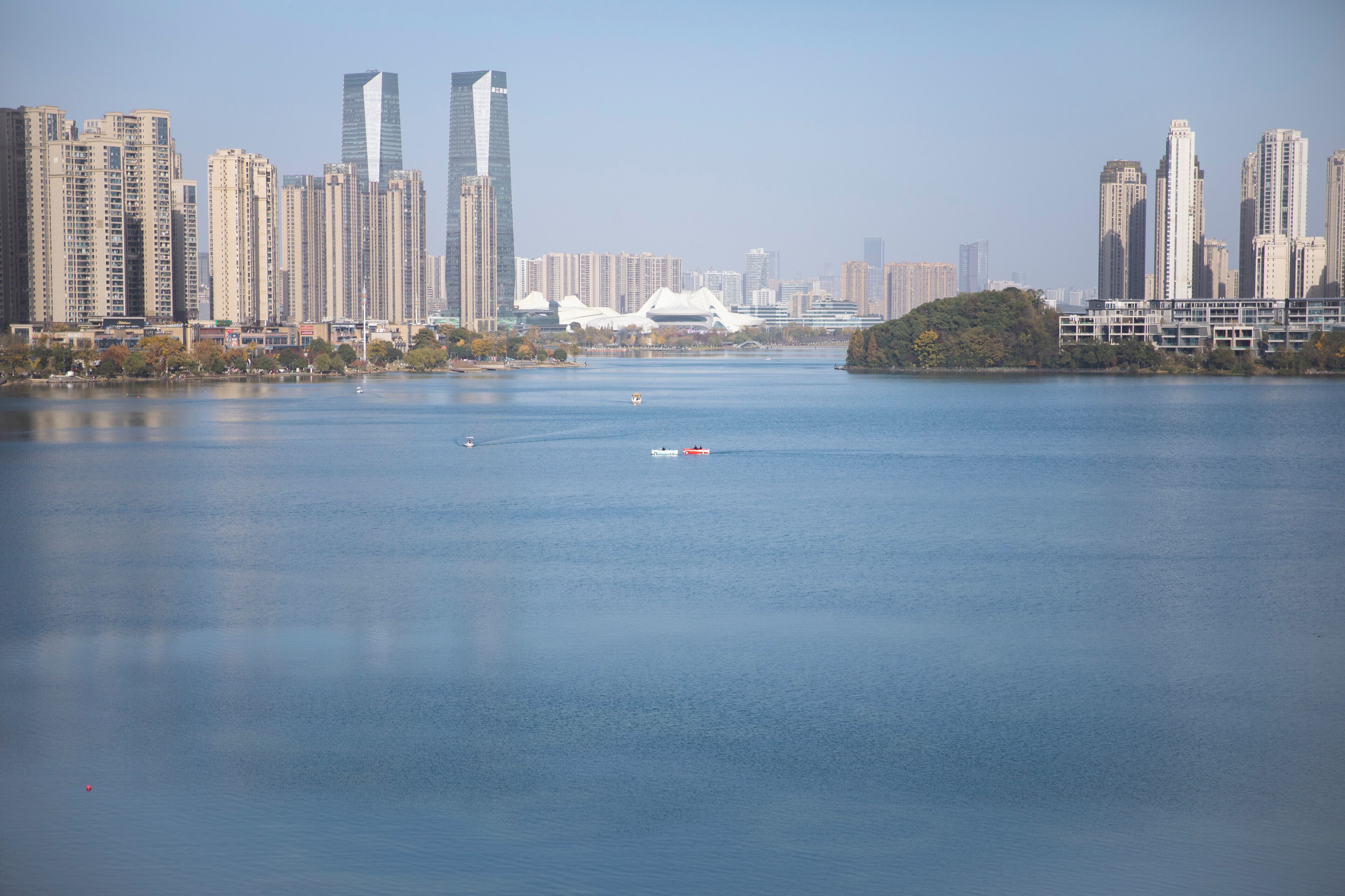 Un río con un paisaje urbano al otro lado, incluyendo rascacielos y una estructura blanca distintiva.