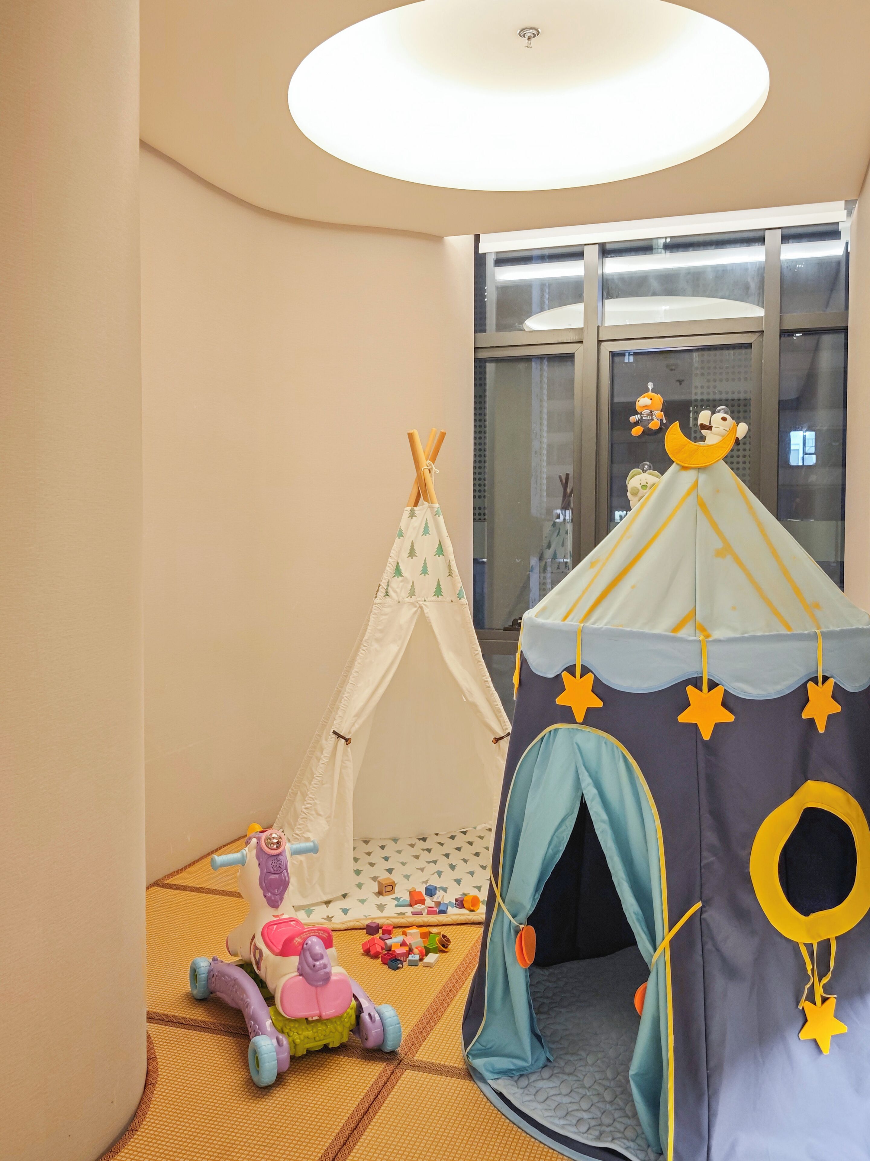 A child's play area with a tent, a playhouse, and toys on a tatami mat floor.