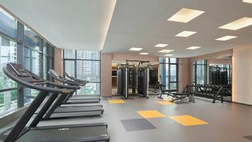 A modern gym with treadmills, weight machines, and a mirror wall.