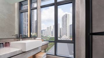 A modern bathroom with a large window, a white sink, and a mirror.