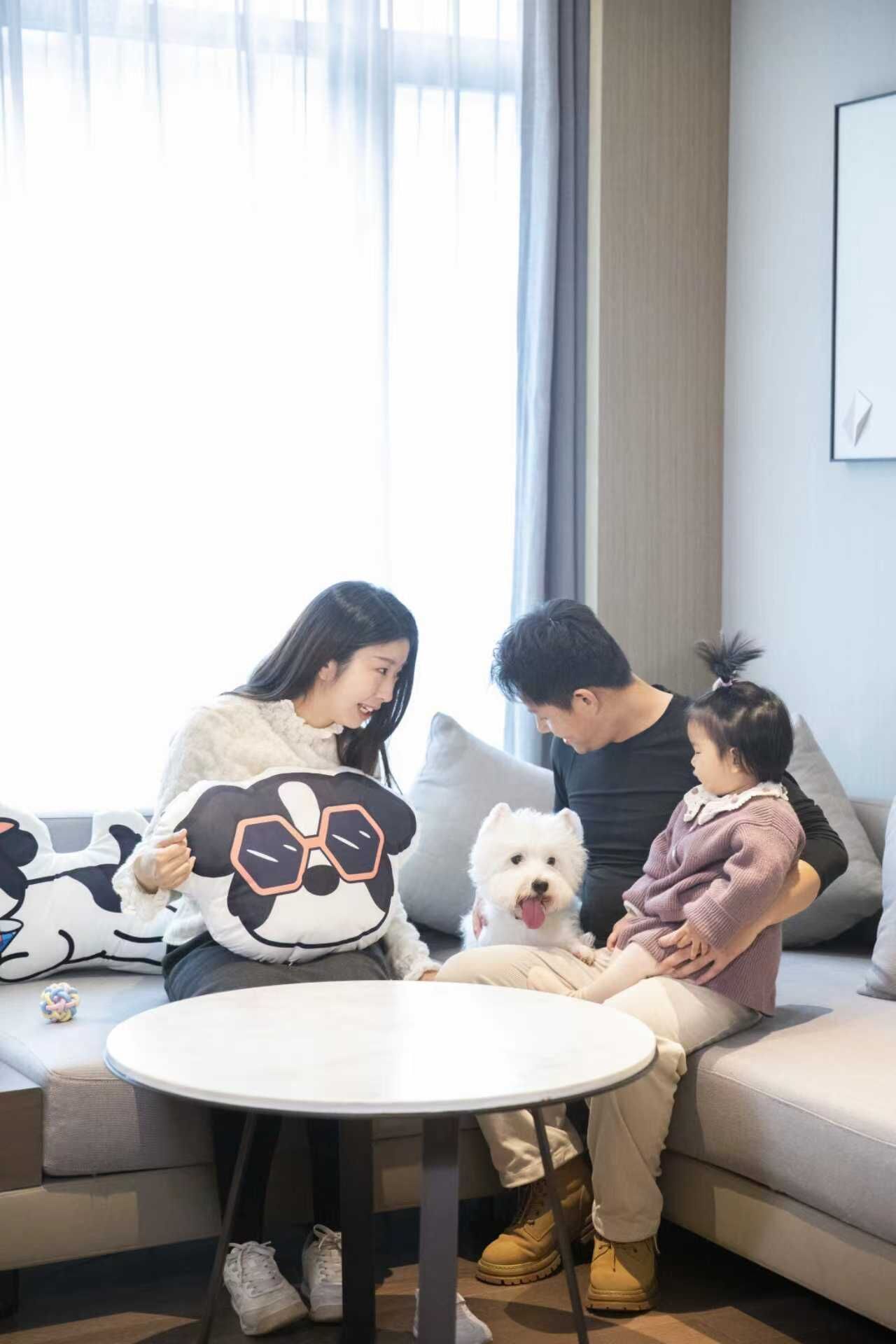 A living room with a sofa, a round coffee table, and a small dog.