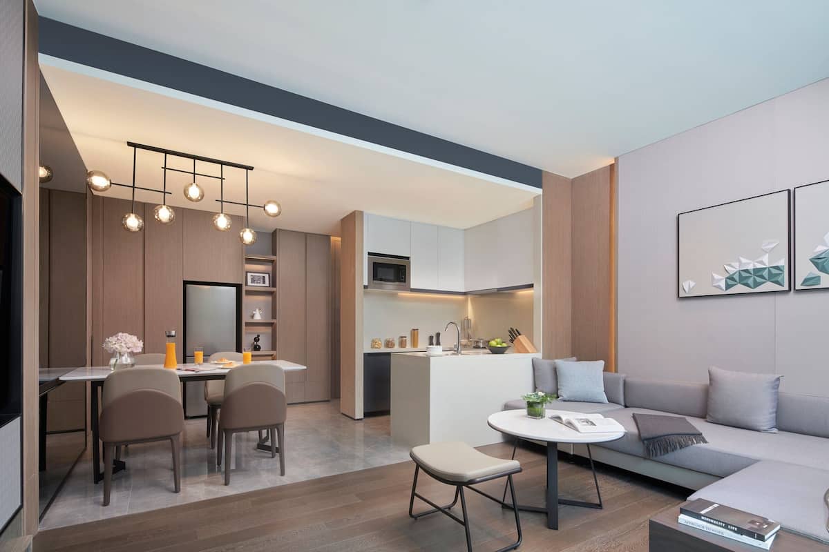 Una cocina moderna con una isla central, una zona de comedor con sillas, un sofá y una mesa de centro.