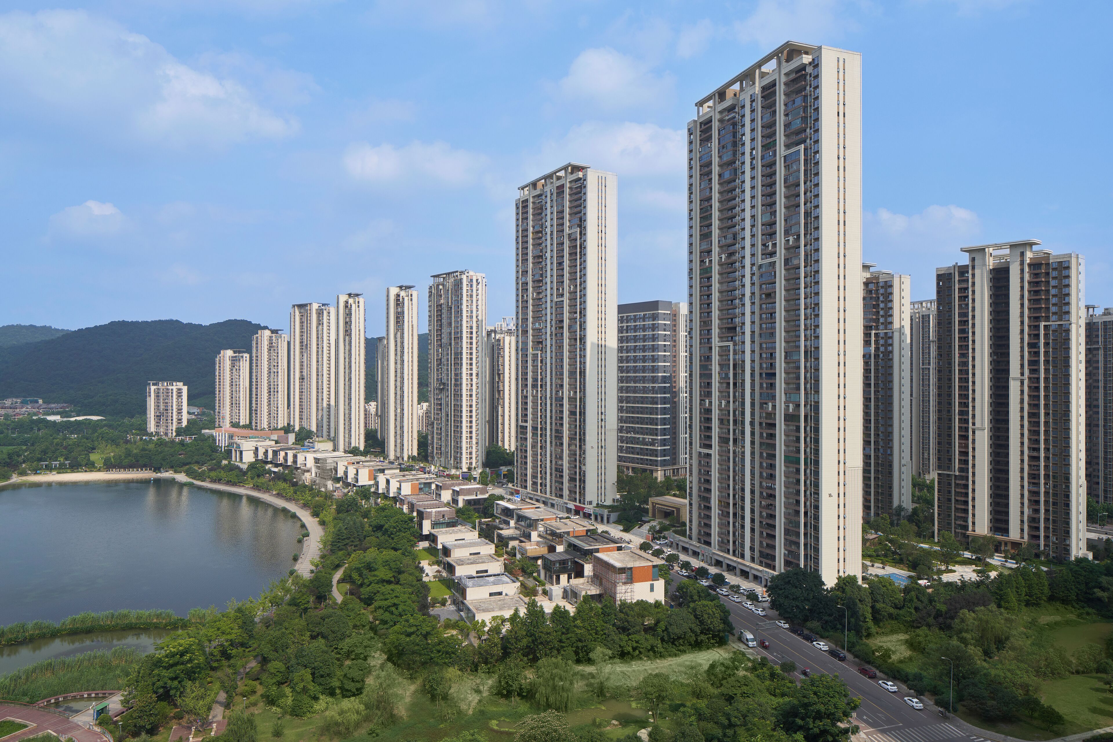 A high-rise residential area with multiple apartment buildings, a road, and a lake.