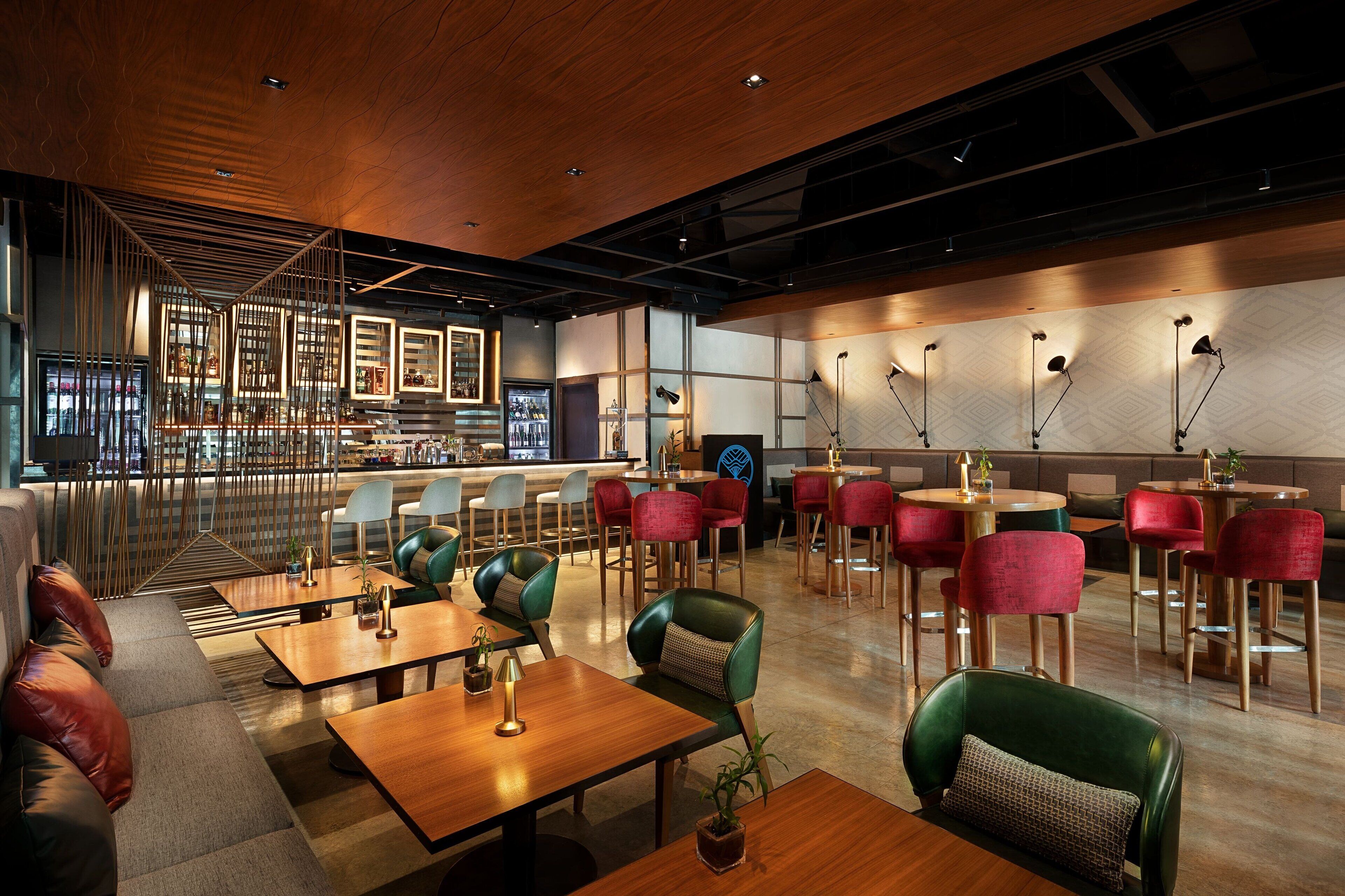 Un restaurant moderne avec des tables et des chaises en bois, un bar et un espace salon avec des canapés et des fauteuils.