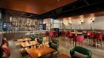 Un restaurant moderne avec des tables et des chaises en bois, un bar et un espace salon avec des canapés et des fauteuils.