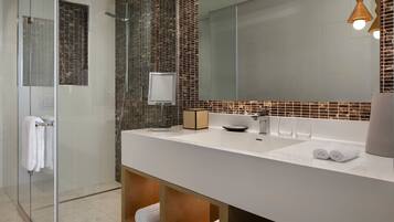 Un bany modern amb una cabina de dutxa de vidre, un lavabo blanc i un mirall gran.