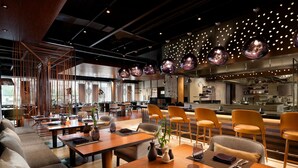 Un interior de restaurante moderno con mesas de madera, asientos cómodos e iluminación colgante.