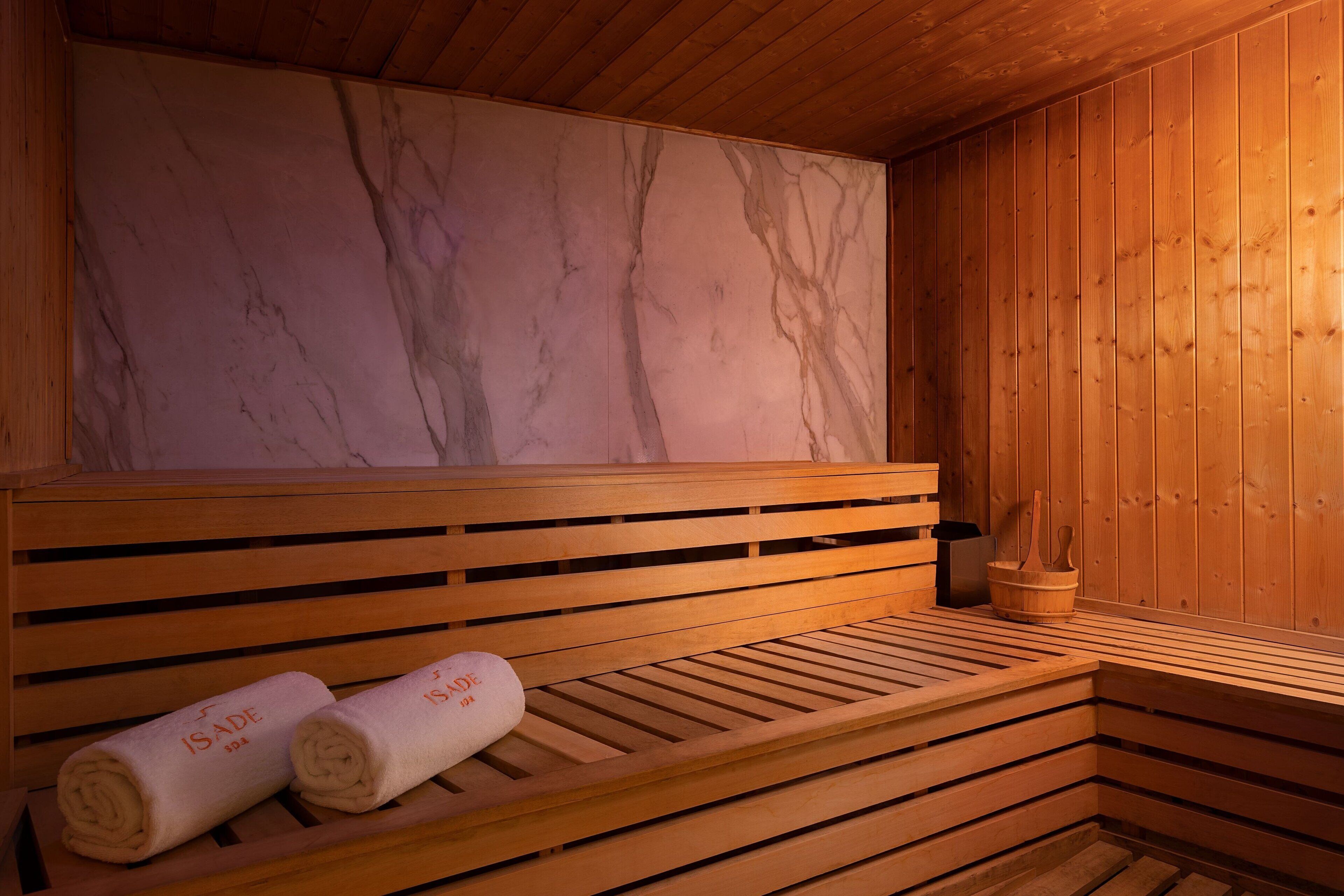 A wooden bench with towels and a marble wall in a sauna room.