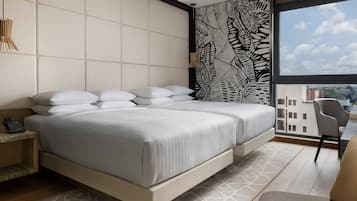 Habitación de hotel moderna con una cama grande, teléfono en la mesita de noche, pared con diseño y vistas a la ciudad a través de un ventanal amplio.