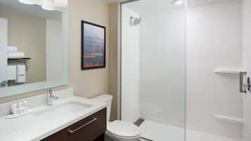 Un baño moderno con un espejo grande, un lavabo y una ducha con mampara de vidrio.
