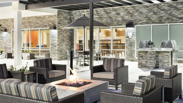An outdoor patio with wicker furniture, a fire pit, and a stone wall.