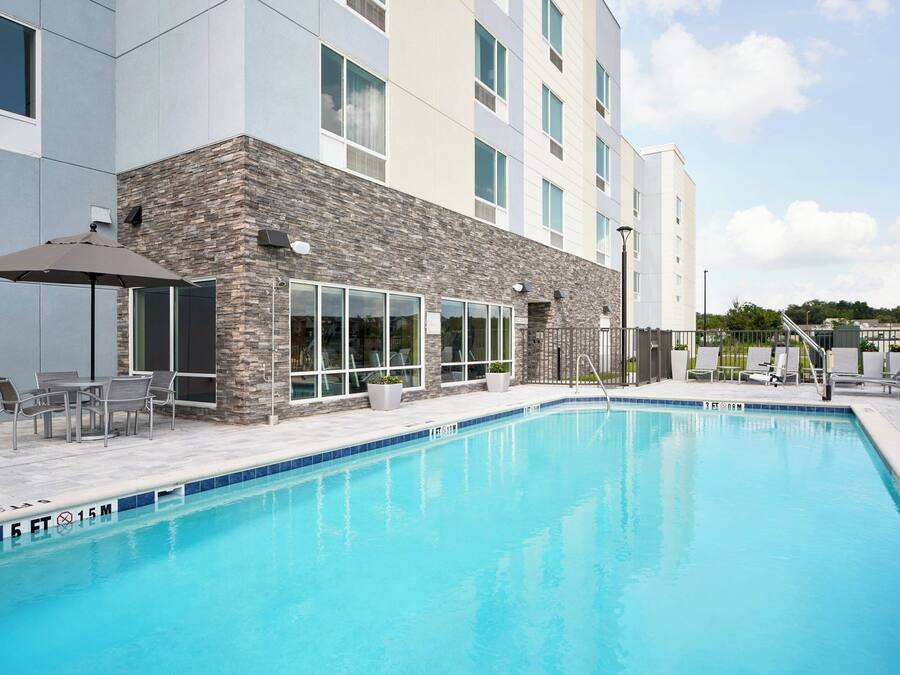 Une piscine avec des chaises longues et un espace patio.