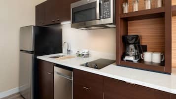 Una cocina moderna con electrodomésticos de acero inoxidable, un microondas integrado, cafetera y un escurreplatos.
