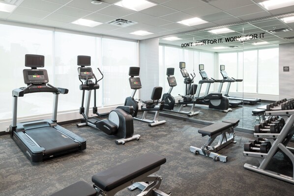 Un gimnasio moderno con cintas de correr, máquinas de pesas y bancos.