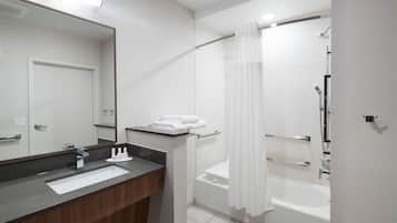 A modern bathroom with a large mirror, a sink, a shower with a glass door, and a bathtub.