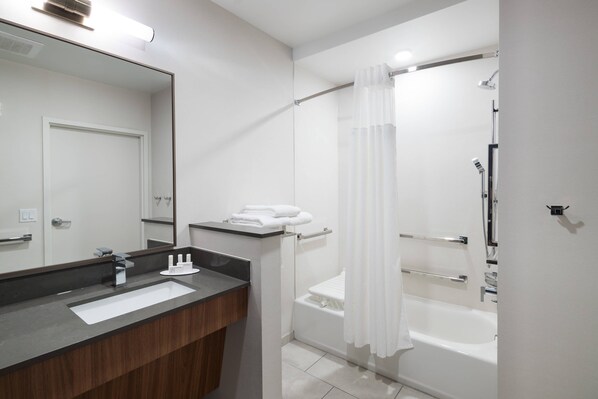 Un baño moderno con un espejo grande, un lavabo, ducha con puerta de cristal y una bañera.
