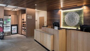 A reception area with a wooden reception desk, a refrigerator stocked with beverages, and a sign indicating the 'Corner Market'.