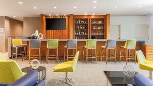 A bar area with wooden bar stools, a flat-screen TV, and shelves of liquor bottles. - SpringHill Suites by Marriott San Jose Fremont (Fremont)