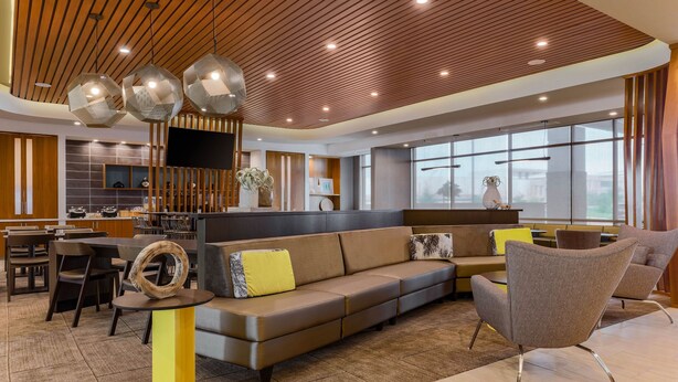 A modern interior with a wooden ceiling, a sofa, a chair, a dining area, and a TV. - SpringHill Suites by Marriott San Jose Fremont (Fremont)