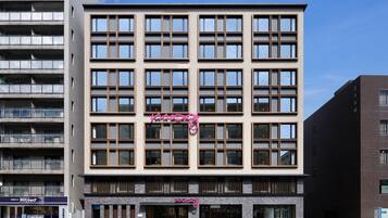 A multi-story hotel with a modern facade, featuring a prominent 'Haas' sign on the ground floor.