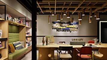 Una biblioteca moderna con un escritorio de madera, varias sillas y un banco acolchado verde.