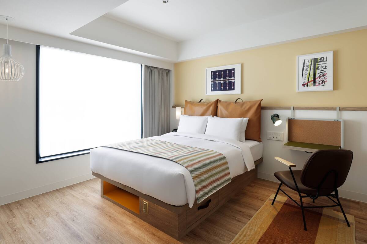 Une chambre d’hôtel moderne, dotée d’un grand lit, d’un bureau et d’une chaise.