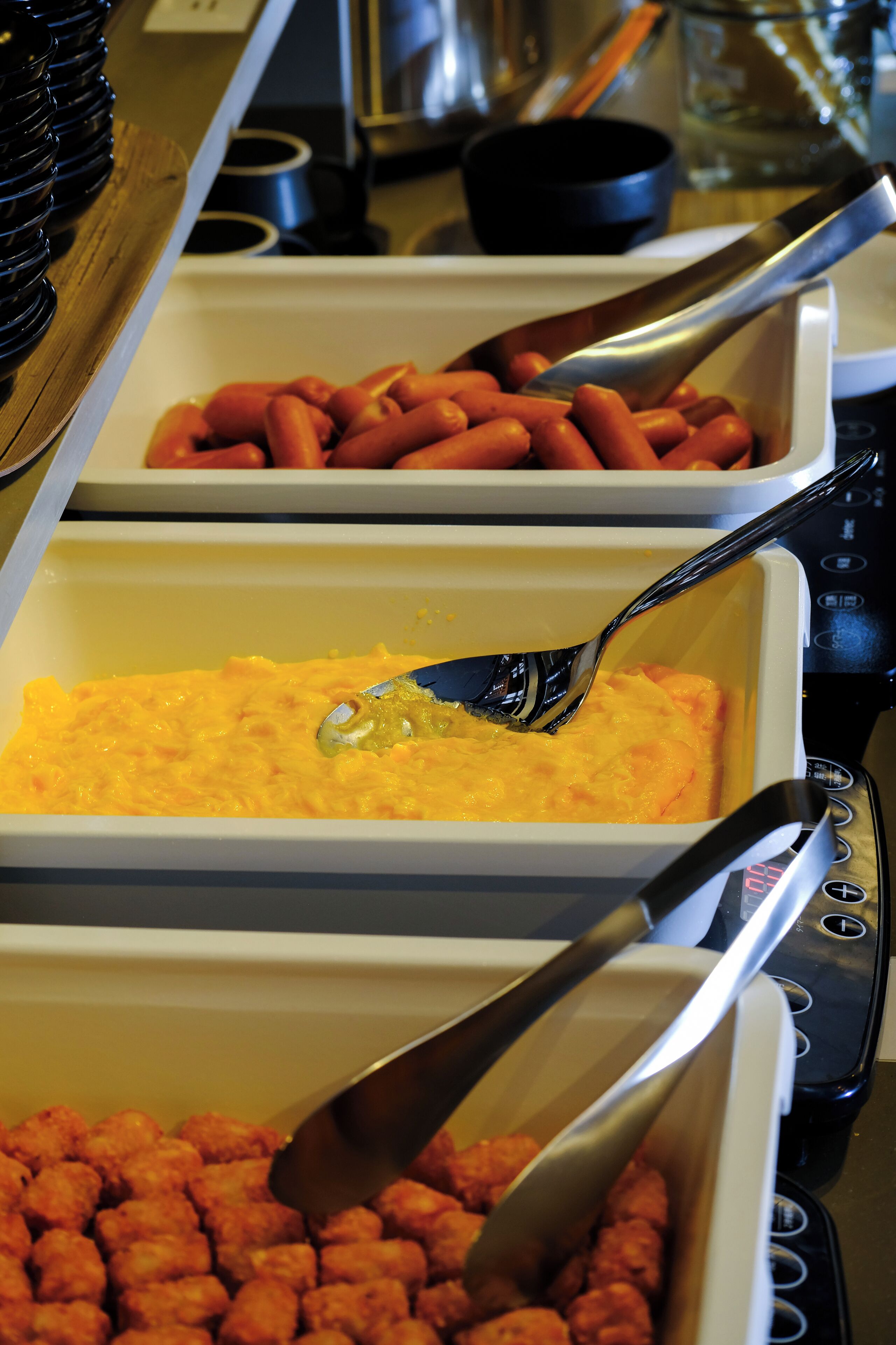 Noutopöydässä on tarjolla erilaisia ruokia, kuten hot dog -leipiä, makaronilaatikkoa ja perunapalloja.