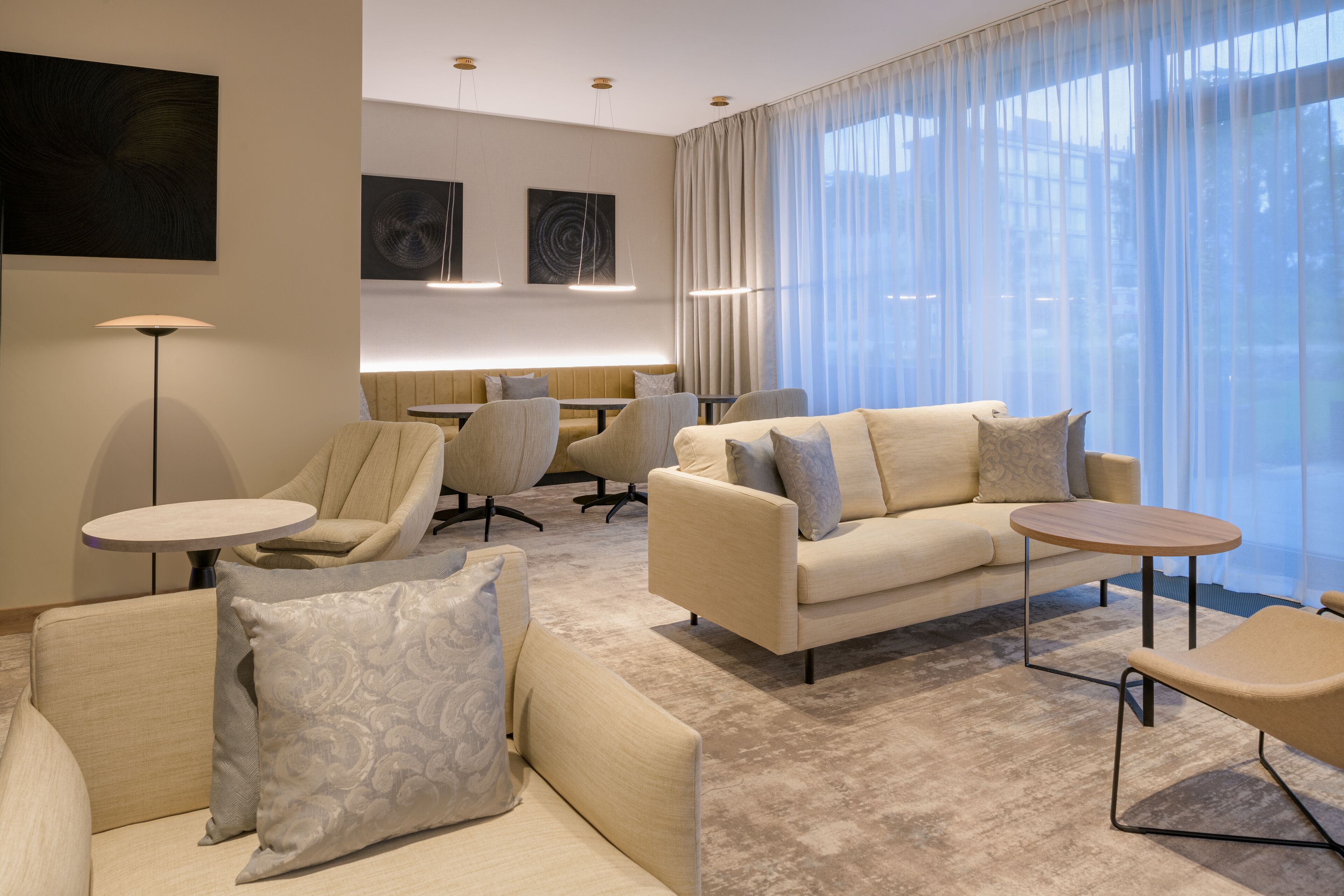 Ein modernes Wohnzimmer mit einer Couch, Sesseln, einem Couchtisch und einem Esstisch.