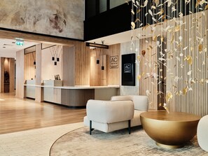 Eine moderne Hotelhalle mit Empfangsbereich, Sitzgelegenheiten und einer Wanddekoration mit hängenden Elementen.