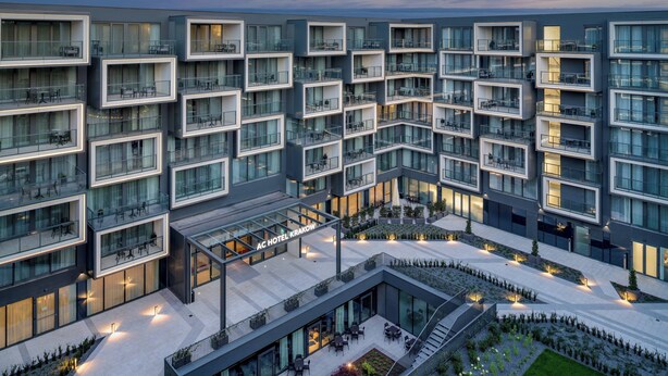 A modern hotel with multiple balconies, outdoor seating areas, and a central courtyard.