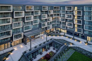 Un hotel moderno con numerosi balconi, zone relax all'aperto e un cortile interno.