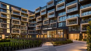 A modern hotel with multiple balconies, a well-lit entrance, and a landscaped courtyard.